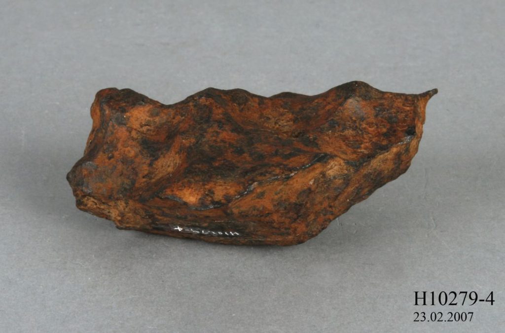 A red and brown mottled rock against a grey background.
